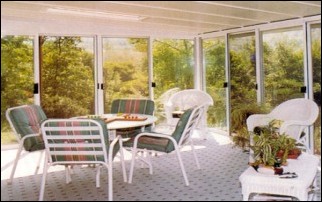 Enclosed All Glass Walled Patio Room With A table And Chairs In The Middle.