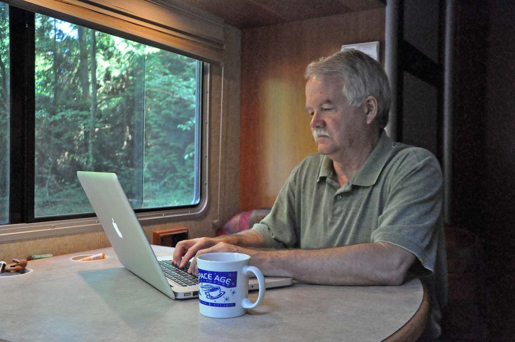 Man Typing At A Computer In An RV.