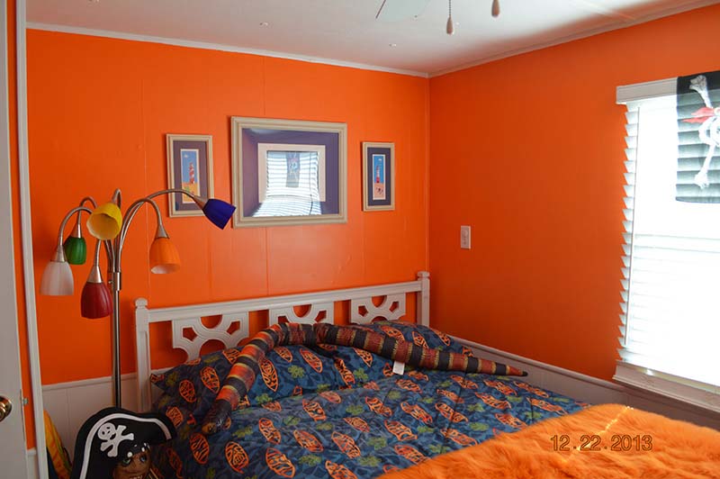 Bedroom With Bright Orange Walls With White Trim At The Bottom.