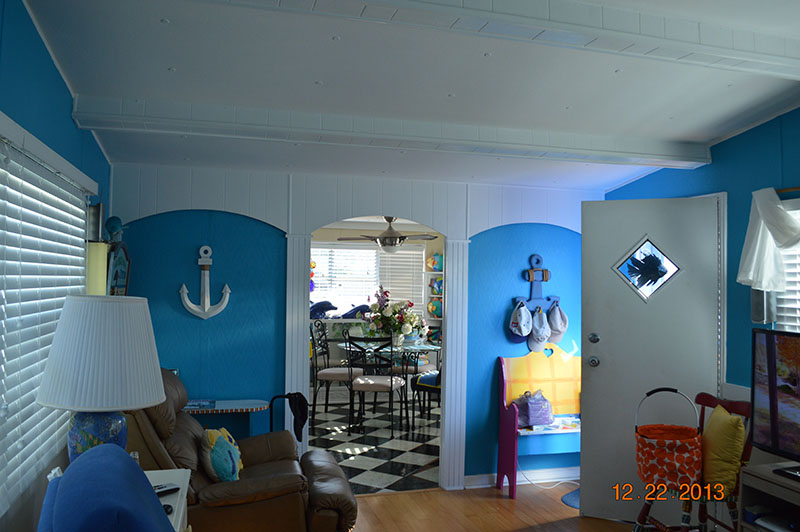 Living Room With Bright Blue Walls And Wood Flooring And Nautical Themed Accent Pieces.