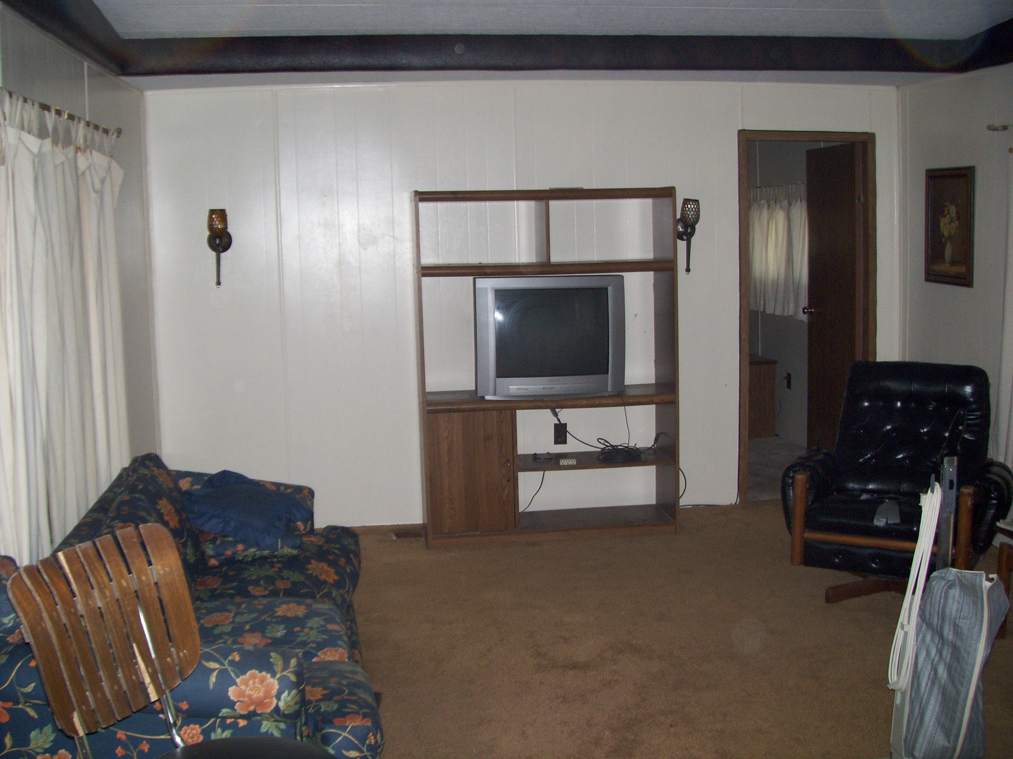 White Wood Paneled Walls, Brown Carpeting and White Floor To Ceiling Drapes.