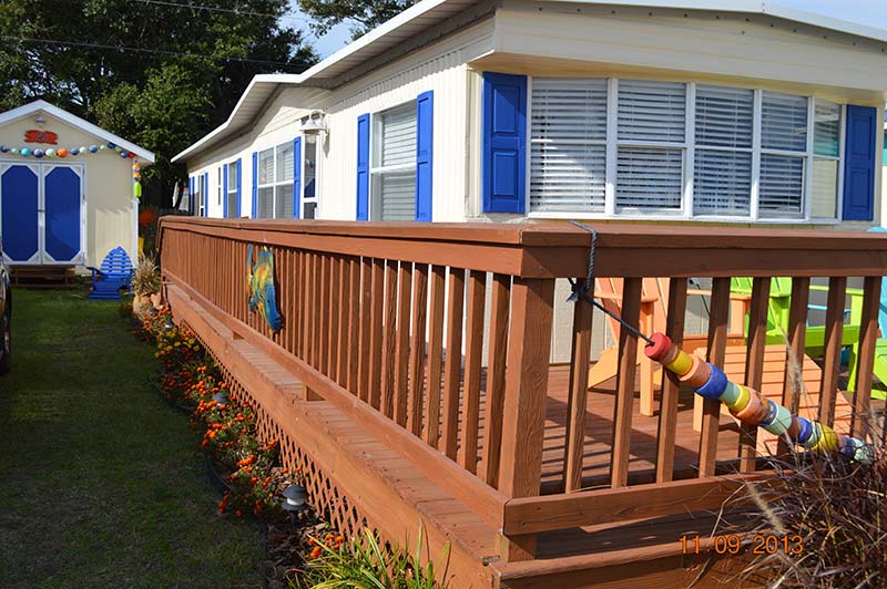 Newly Painted White Mobile Home With Blue Shutters And A Newly Painted Brown Porch Porch.