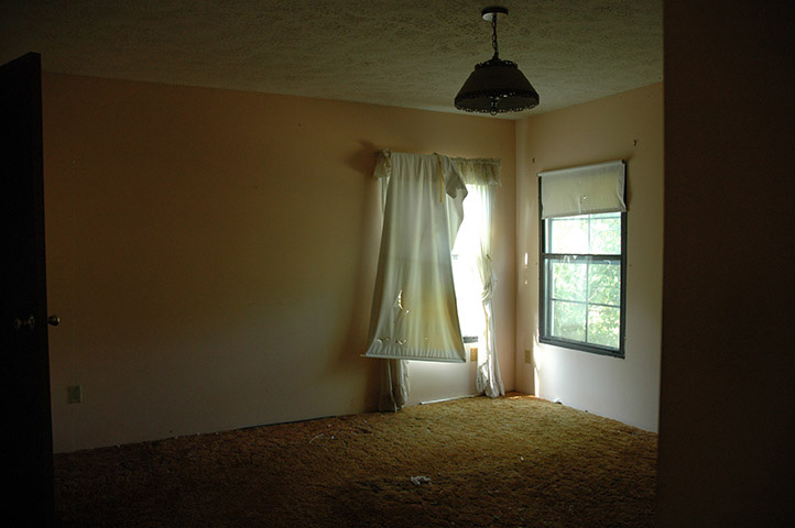 Room With Torn And Stained Curtains And Orange Discolored And Stained Carpet.