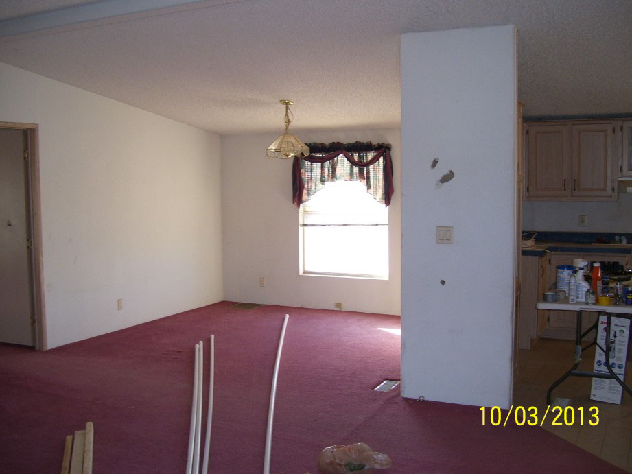 Dining Room With White Damaged Walls And Red Carpeting.