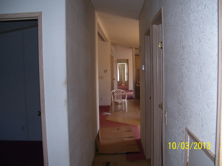 Hallway With White Walls And Red Carpeting With Cardboard Over The Walking Path.