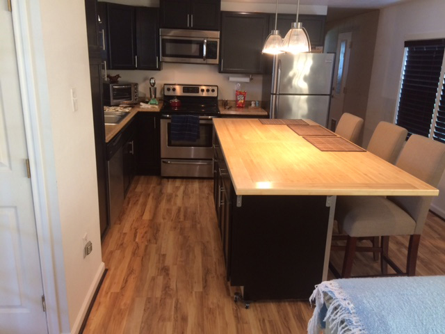 Updated Kitchen With New Wood Floors, A New Wooden Island And All New Black Cabinets.