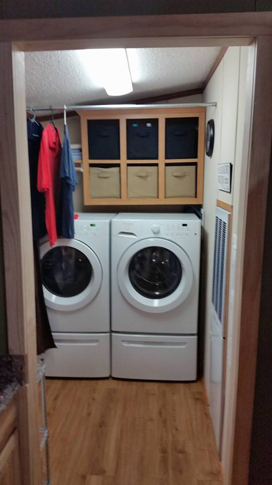 Laundry Room With Front Loading Washer And Dryer With Storage Above Them.