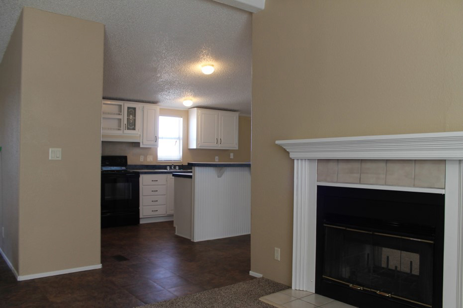 Living Room With White Trimmed Fire Places And The Kitchen With White Cabinets And A Black Stove.