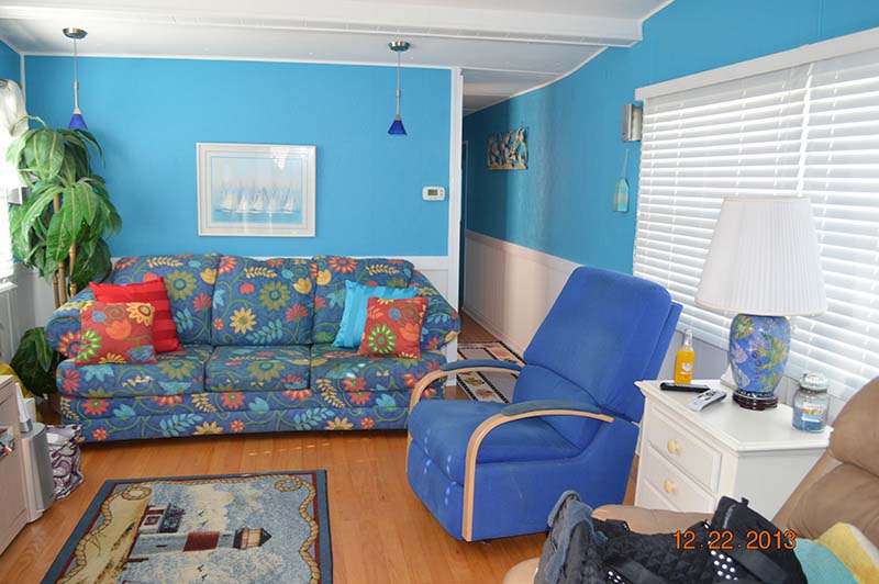 Living Room With Bright Blue Walls On The Top Half And White Paneling on The Bottom.