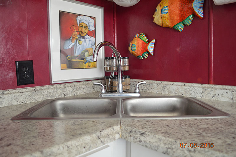 Stainless Steel Sink With Red Wall Behind It.