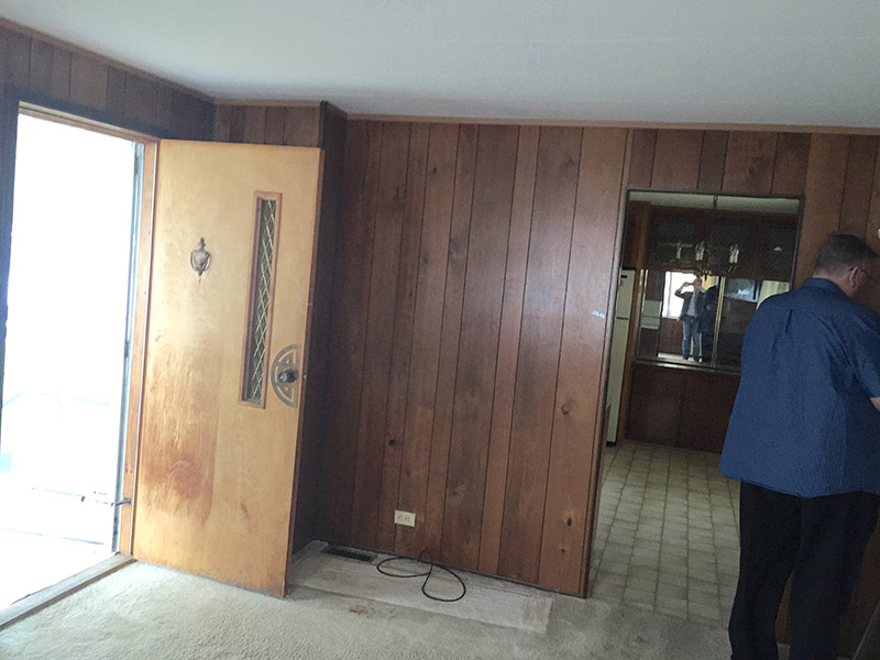 An Old Discolored Wooden Door, Dirty White Carpet And Aged Wooden Wall Paneling.