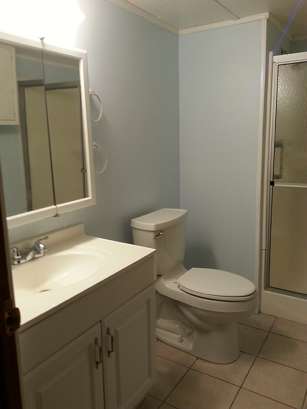 Bathroom With Blue Walls, White Sink, Toilet And Mirrors.