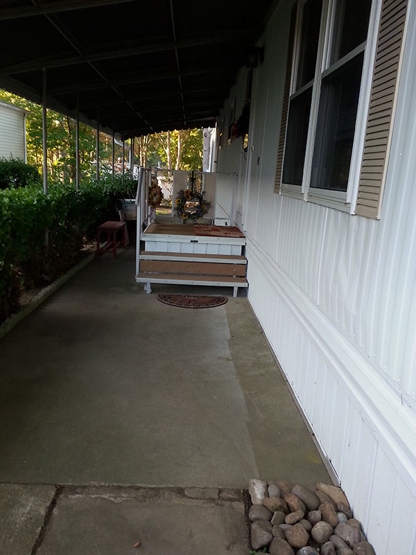 Front Door Area Of Mobile Home, With A Small Square Porch In Front Of The Door.
