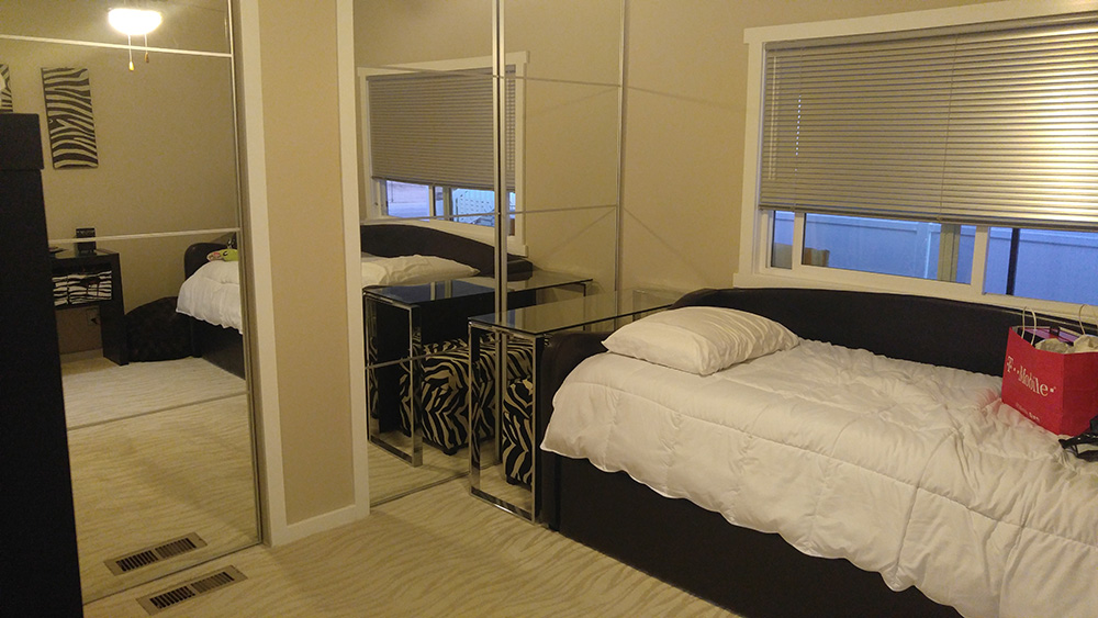 Guest Bedroom With Beige Walls With White Accents And Mirrored Closet Doors.