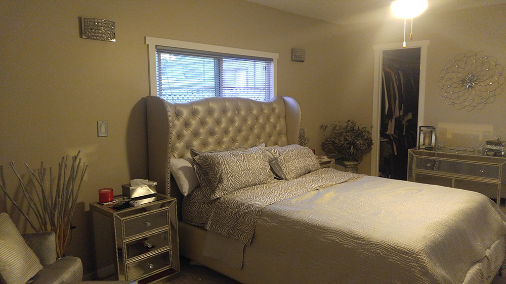 Large Silver Colored Bed With A Padded Headboard and Matching Colored Walls.