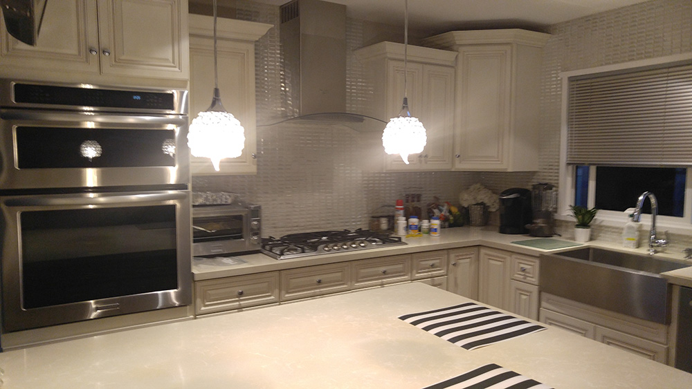 Kitchen With A Large Stainless Steel Sink, White Cabinets And A White Tile Backsplash.