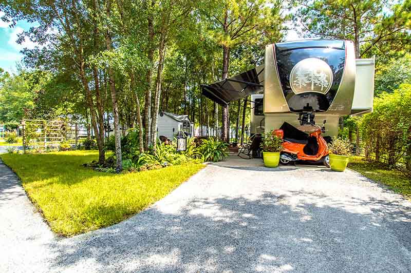 RV Parked Under Trees With A Scooter.
