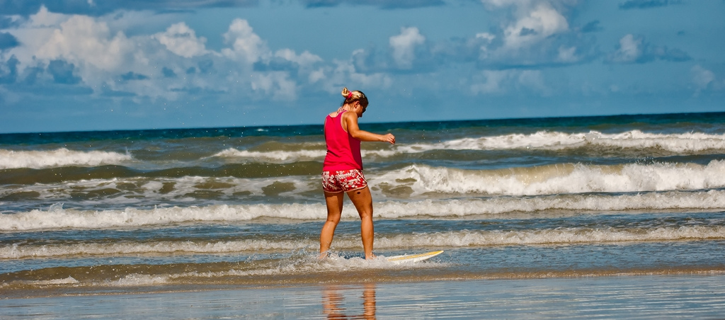 Woman On A Surfboard At The Beach.