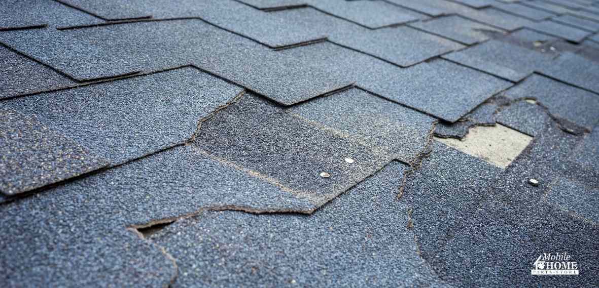mobile home damaged roof with missing and broken shingles
